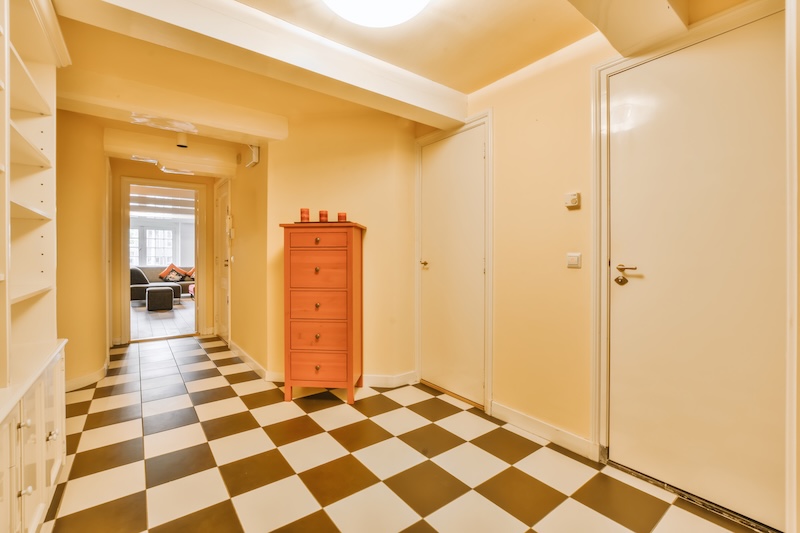 żółty przedpokój z wysoką komodą z drewna 