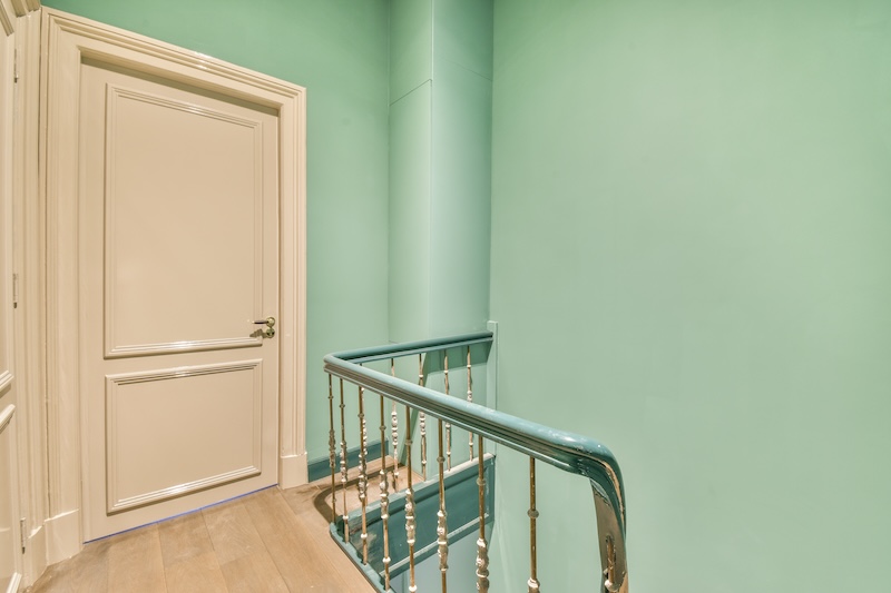 miętowe ściany i białe drzwi w wąskim przedpokoju