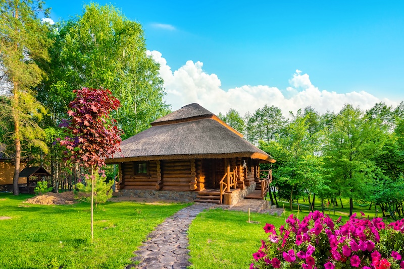 drewniany domek letniskowy w naturze domek z bali z dachem ze strzechy w ogrodzie
