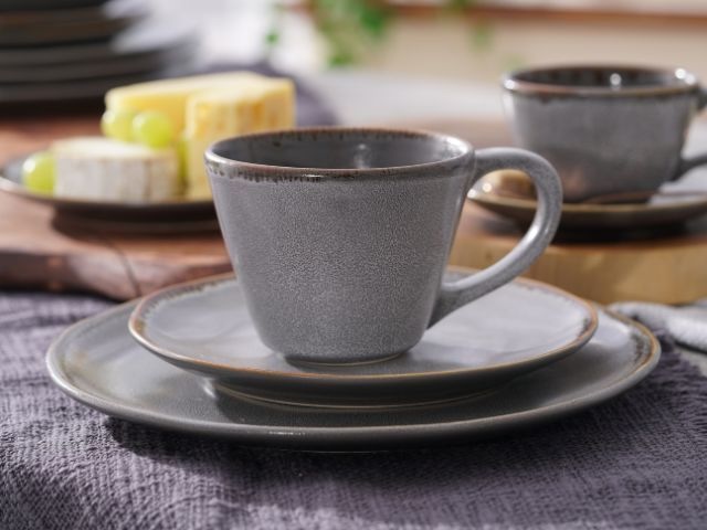 kubek z uchem z szarej ceramiki na talerzu ceramiczny kubek z kuchem na dwóch talerzach